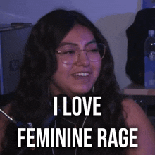 a woman wearing glasses says i love feminine rage while smiling