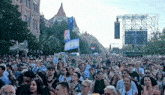 a crowd of people are gathered in front of a large screen .