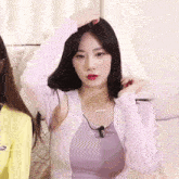a woman in a purple tank top has a necklace with the letter e on it