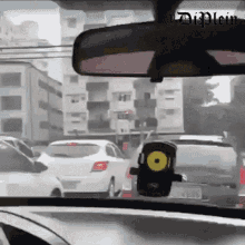the rear view mirror of a car shows a busy city street with a phone holder in the foreground