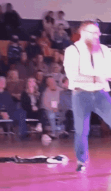 a man in suspenders is dancing on a basketball court in front of a crowd