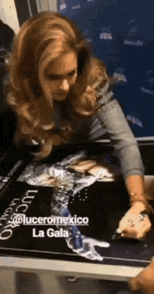 a woman signing a poster for lucero mexico la gala