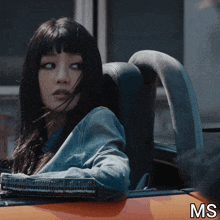 a woman is sitting in the back seat of an orange car with the letters ms below her