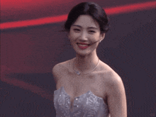 a woman in a strapless dress is smiling and looking at the camera