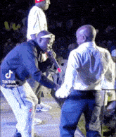 a man is holding a microphone while another man stands behind him on stage .