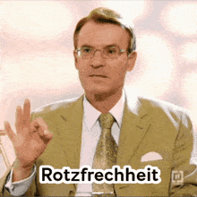 a man in a suit and tie is giving the ok sign and the word rotzfrechheit is above him