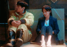 a man and a woman are sitting next to each other on a cardboard box ..