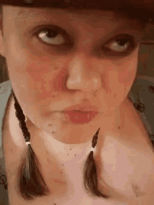 a close up of a woman 's face with pigtails and a cowboy hat .