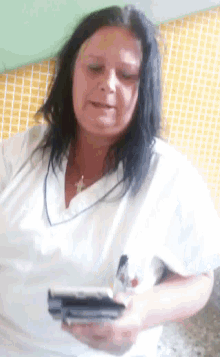 a woman in a white shirt is holding a cell phone and a pen