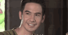 a man is smiling and looking at the camera while wearing a green shirt .