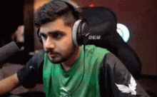 a man wearing headphones and a green shirt is sitting in a chair .