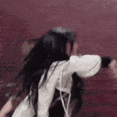 a woman with long black hair is wearing a white jacket and dancing .
