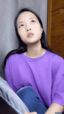 a woman in a purple shirt is looking up at something