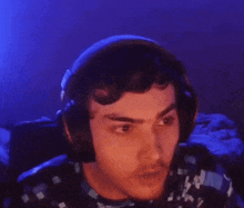 a young man wearing headphones is looking at the camera .
