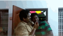 a man in a green and black striped shirt holds another man 's hand