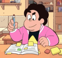 steven universe is sitting at a table with a book and a pen .