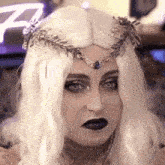a woman wearing a white wig and a crown on her head .