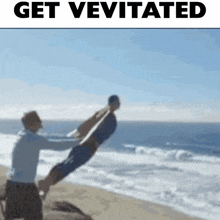 a man is holding another man up in the air on a beach with the words get vevitated above them