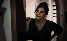 a woman in a black dress is standing in front of a door .