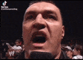 a close up of a man 's face with a microphone in his mouth .
