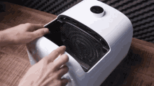 a person is opening a white box with a clock on the top of it