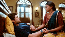 a man is laying on a bed while a woman looks on