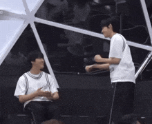 two young men are standing next to each other in front of a large white umbrella .