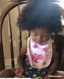 a baby wearing a bib is sitting in a chair with a xrecorder watermark