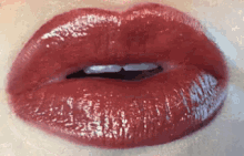 a close up of a woman 's red lips with lipstick on them .