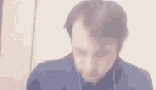 a man wearing headphones and a blue shirt is looking down .