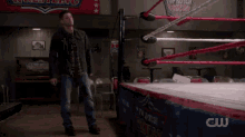 a person is falling into a wrestling ring with a cw logo in the corner