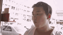 a man in a white shirt is standing in front of a window with his mouth open .