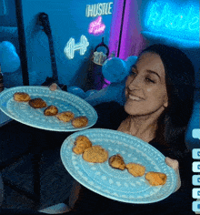 a woman holding two plates of food in front of a sign that says hustle
