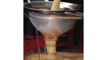 a strainer is being used to strain liquid into a measuring cup .
