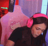 a woman wearing pink headphones is sitting on a chair with a hello kitty on it .