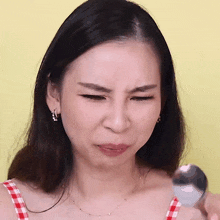 a woman is making a funny face while holding a silver spoon