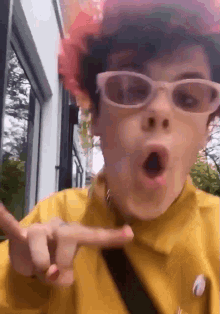 a person wearing sunglasses and a yellow shirt making a funny face