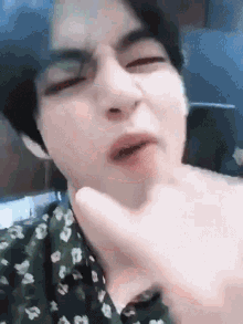 a close up of a person making a funny face with their hand on their neck .