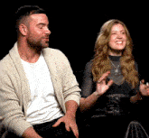 a man and a woman are sitting next to each other and the woman is wearing a necklace