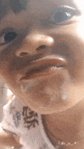 a close up of a child 's face with a white liquid coming out of her mouth