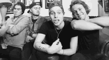 a group of men are sitting on a couch making funny faces .
