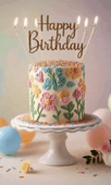 a birthday cake with flowers and butterflies on it is on a cake stand with candles .