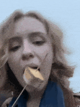a close up of a woman eating a piece of food on a stick .
