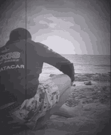 a man sits on the beach wearing a six attack hoodie