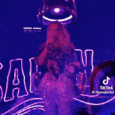 a woman is sitting on a stage in front of a neon sign .