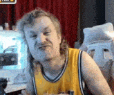 a man with long hair is making a funny face while wearing a yellow tank top .