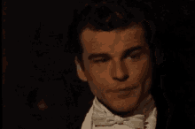a man in a tuxedo and bow tie is looking down at something