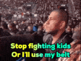 a man sitting in a stadium with the words stop fighting kids or i 'll use my belt below him