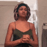 a woman in a green tank top is wearing a satin bonnet on her head