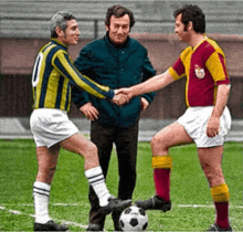 two soccer players shaking hands with a man wearing a blue jacket